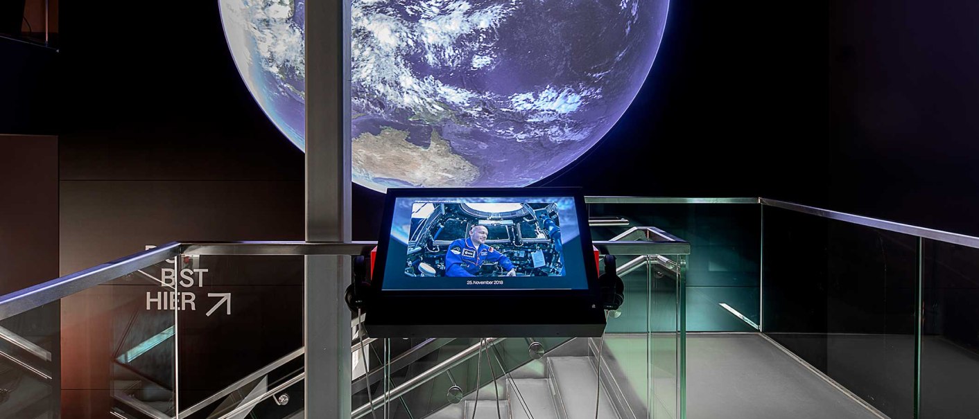 Ausstellung mit großem Bild der Erde und Bildschirm mit Astronautenfoto im Haus der Geschichte Baden-Württemberg., © Haus der Geschichte Baden-Württemberg, Daniel Stauch Photography Ausstellung mit großem Bild der Erde und Bildschirm mit Astronautenfoto im Haus der Geschichte Baden-Württemberg., © Haus der Geschichte Baden-Württemberg, Daniel Stauch Photography