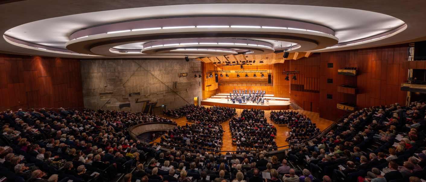 A large concert hall with a modern design, filled with spectators. An orchestra plays on the stage. The architecture is impressive., &copy; Holger Schneider