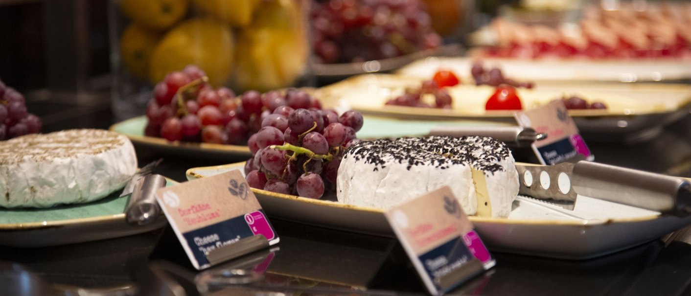 Breakfast buffet with cheese and grapes on plates. In the foreground a cheese knife and inscriptions., &copy; MASEVEN Stuttgart SI-Centrum