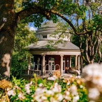 A round teahouse with pillars in Weissenburg Park, surrounded by green trees and blooming flowers in the foreground., &copy; Thomas Niederm&uuml;ller