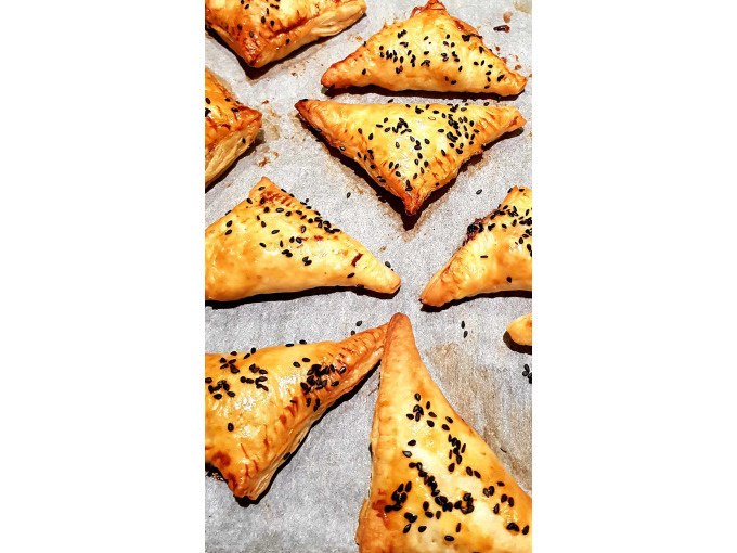 Golden-brown, triangular dumplings sprinkled with black sesame seeds and baked on baking paper., © Kultweine-Kochwelten-Kunstücke - Kochschule Sonja Lenz Golden-brown, triangular dumplings sprinkled with black sesame seeds and baked on baking paper., © Kultweine-Kochwelten-Kunstücke - Kochschule Sonja Lenz