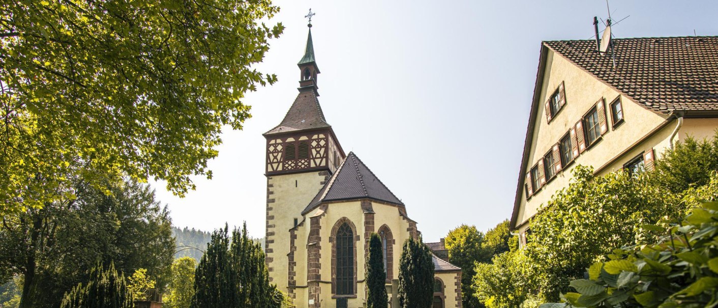 Church in Bad Liebenzell with half-timbered tower, surrounded by trees and a residential building in sunny weather., © Stuttgart-Marketing GmbH, Sarah Schmid Church in Bad Liebenzell with half-timbered tower, surrounded by trees and a residential building in sunny weather., © Stuttgart-Marketing GmbH, Sarah Schmid