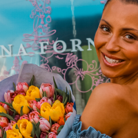 Woman with a bouquet of flowers smiles in front of a shop window with the lettering 'Ilona Forner'., &copy; Ilona Forner, Stuttgart
