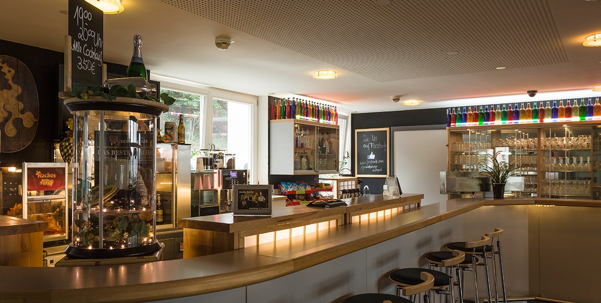 A cozy bistro with a long counter, bar stools and decorative bottles on shelves. A sign advertises cocktails., © TOMAS A cozy bistro with a long counter, bar stools and decorative bottles on shelves. A sign advertises cocktails., © TOMAS