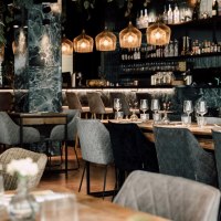 Elegant restaurant with modern furniture, laid tables and a stylish bar in the background. Subtle lighting and plants create a cozy atmosphere., &copy; Malo Stuttgart - Lea Prestle