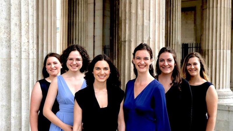 Sechs Frauen in eleganter Kleidung posieren l&auml;chelnd vor einem historischen Geb&auml;ude mit S&auml;ulen., &copy; Stiftsmusik Stuttgart