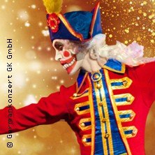 Ein Tänzer in einem farbenfrohen Nussknacker-Kostüm mit roter Uniform und blauem Hut, lächelnd vor einem glitzernden, goldenen Hintergrund., © links im Bild Ein Tänzer in einem farbenfrohen Nussknacker-Kostüm mit roter Uniform und blauem Hut, lächelnd vor einem glitzernden, goldenen Hintergrund., © links im Bild