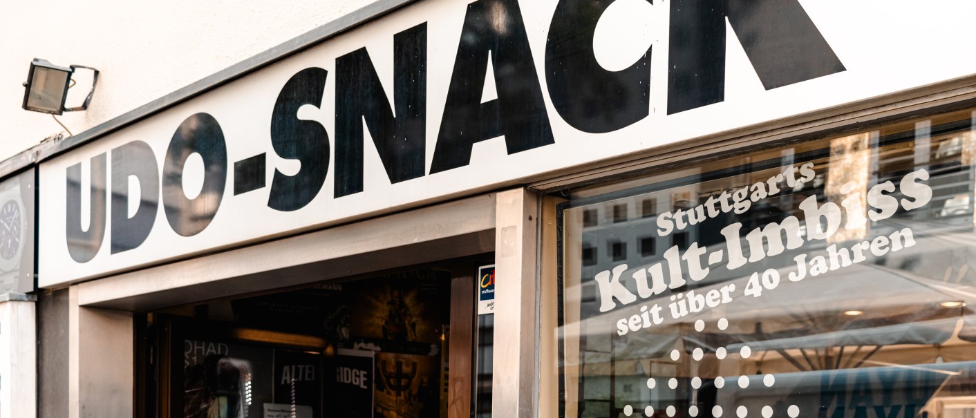 Eingang zu Udo-Snack in Stuttgart, mit großem Schild und Fensteraufdruck 'Kult-Imbiss seit über 40 Jahren'., © SMG_Sarah Schmid Eingang zu Udo-Snack in Stuttgart, mit großem Schild und Fensteraufdruck 'Kult-Imbiss seit über 40 Jahren'., © SMG_Sarah Schmid