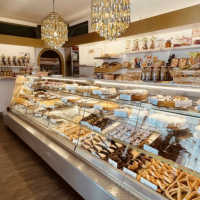 Ein gem&uuml;tliches Caf&eacute; mit einer Vitrine voller Geb&auml;ck und Schokolade. Dekorative Figuren und ein Kronleuchter erg&auml;nzen das Ambiente., &copy; FreCla Gastronomiebetriebe GmbH