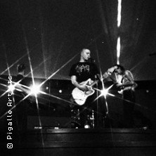 Band auf der B&uuml;hne mit Gitarren, Lichteffekte im Hintergrund. Schwarz-wei&szlig; Bild, dynamische Pose der Musiker., &copy; links im Bild