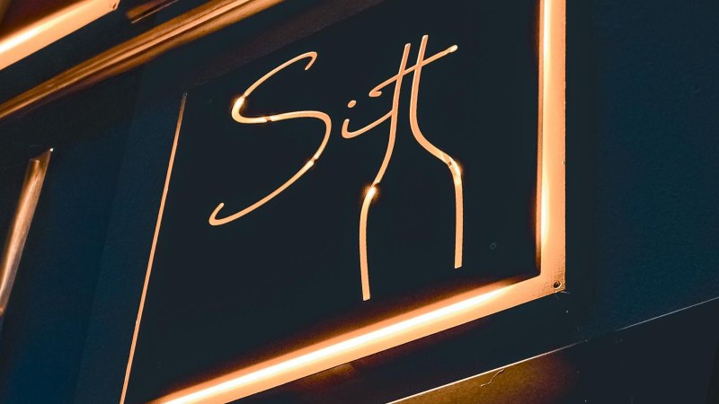 Neonschild mit der Aufschrift 'Sitt' und einer stilisierten Flasche in warmem Licht., © Sitt Wein, Stuttgart Neonschild mit der Aufschrift 'Sitt' und einer stilisierten Flasche in warmem Licht., © Sitt Wein, Stuttgart