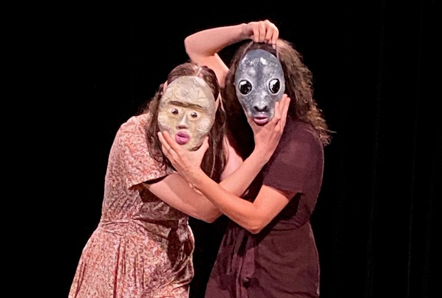 Zwei Personen auf einer Bühne tragen ausdrucksstarke Masken und posieren in einer dramatischen Geste vor einem schwarzen Hintergrund., © Wilhelma Theater Zwei Personen auf einer Bühne tragen ausdrucksstarke Masken und posieren in einer dramatischen Geste vor einem schwarzen Hintergrund., © Wilhelma Theater