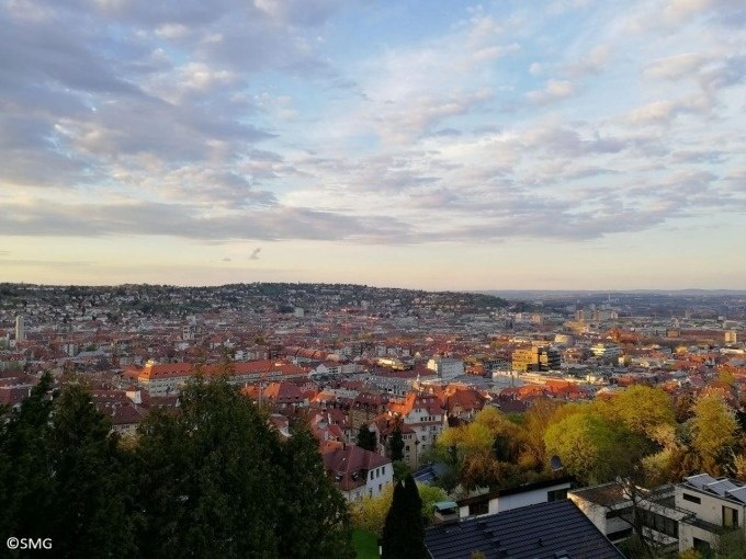 Panoramablick über Stuttgart mit roten Dächern, bewaldeten Hügeln und einem weiten Himmel mit Wolken im Hintergrund., © Stuttgart Marketing GmbH Panoramablick über Stuttgart mit roten Dächern, bewaldeten Hügeln und einem weiten Himmel mit Wolken im Hintergrund., © Stuttgart Marketing GmbH