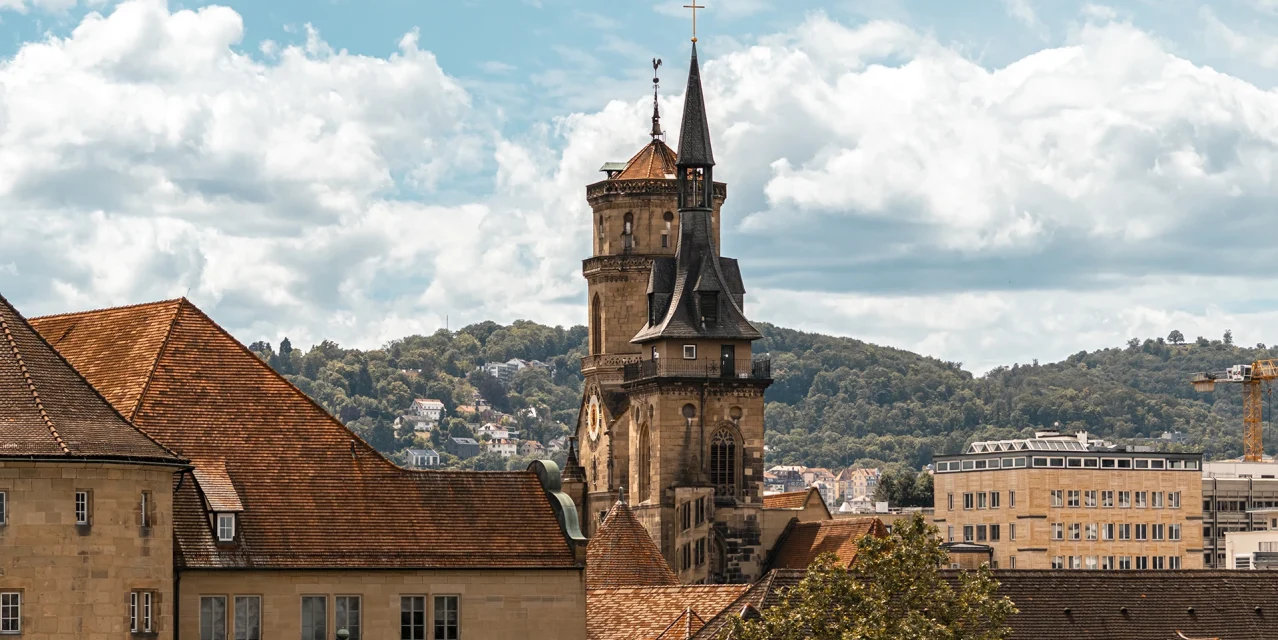 Blick auf die Stiftskirche mit Turm, roten Dächern und bewaldeten Hügeln im Hintergrund., © SMG, Sarah Schmid Blick auf die Stiftskirche mit Turm, roten Dächern und bewaldeten Hügeln im Hintergrund., © SMG, Sarah Schmid