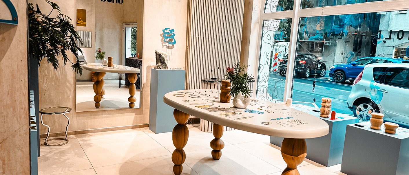 Modern studio with wooden table, mirror and decorations. Large window front with a view of the street. Plants and art objects as decoration., © Goldmarlen Modern studio with wooden table, mirror and decorations. Large window front with a view of the street. Plants and art objects as decoration., © Goldmarlen