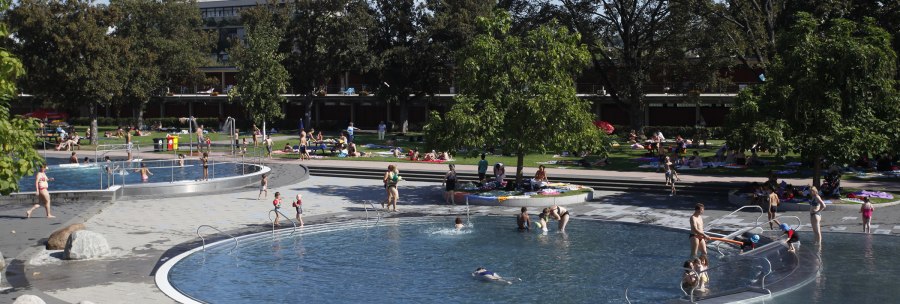Das Inselbad Stuttgart-Untertürkheim zeigt Menschen, die an einem sonnigen Tag in Pools schwimmen und auf grünen Wiesen entspannen., © Stuttgarter Bäder Das Inselbad Stuttgart-Untertürkheim zeigt Menschen, die an einem sonnigen Tag in Pools schwimmen und auf grünen Wiesen entspannen., © Stuttgarter Bäder