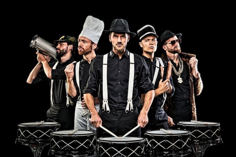 Five men in black clothing and various hats pose with drums. They wear accessories such as a chef's hat and a gold chain., &copy; Theaterhaus Stuttgart e.V.