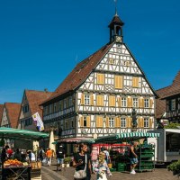 The market square in Winnenden shows half-timbered houses and market stalls under a clear blue sky. People stroll and shop., &copy; Stuttgart-Marketing GmbH, Sarah Schmid