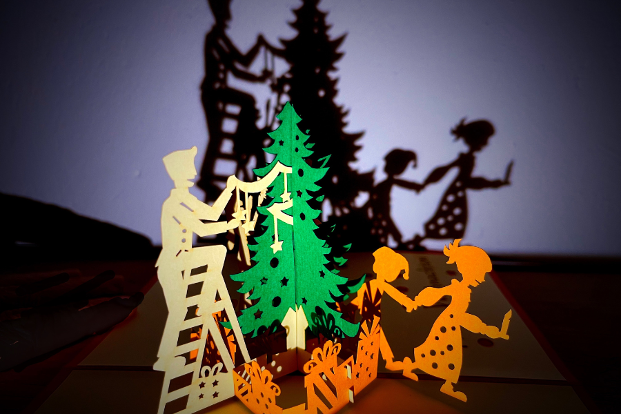 Papierfiguren dekorieren einen Weihnachtsbaum. Ihre Schatten an der Wand erz&auml;hlen eine festliche Geschichte. Ein kreatives Weihnachtsarrangement., &copy; Sch&auml;fer/Theater in der Badewanne