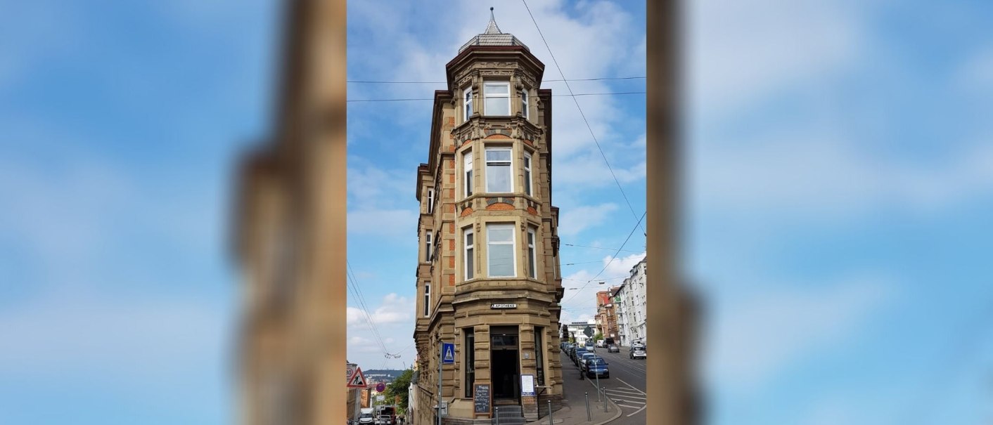 Historisches Eckgebäude mit Apotheke im Erdgeschoss, umgeben von Straßen und Autos, unter blauem Himmel., © SMG Historisches Eckgebäude mit Apotheke im Erdgeschoss, umgeben von Straßen und Autos, unter blauem Himmel., © SMG