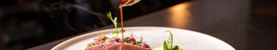 An artfully prepared gourmet dish with meat, vegetables and a dark sauce that is poured onto the plate from a ladle., &copy; 5 - Stuttgart