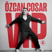 A man in a suit poses in front of large red lettering '&Ouml;zcan Cosar VIP' on a wall., &copy; links im Bild