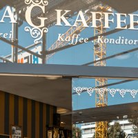 Eingang des Glora Kaffeehauses mit dekorativem Schriftzug auf der Glasfront. Im Hintergrund sind Baukr&auml;ne zu sehen., &copy; SMG, Sarah Schmid
