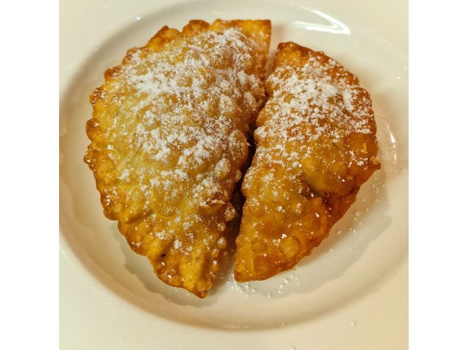 Two golden-brown, deep-fried dumplings, sprinkled with powdered sugar, lie on a white plate., © Kultweine-Kochwelten-Kunstücke - Kochschule Sonja Lenz Two golden-brown, deep-fried dumplings, sprinkled with powdered sugar, lie on a white plate., © Kultweine-Kochwelten-Kunstücke - Kochschule Sonja Lenz