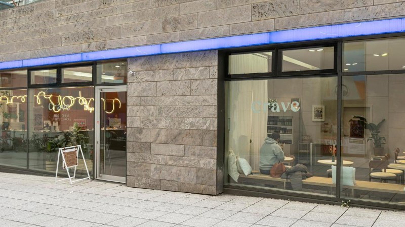 Gro&szlig;e Fensterfronten, die Blick auf das Caf&eacute; im Inneren freigeben: Holztische, wei&szlig;e Kissen., &copy; Stuttgart-Marketing GmbH, Sarah Schmid