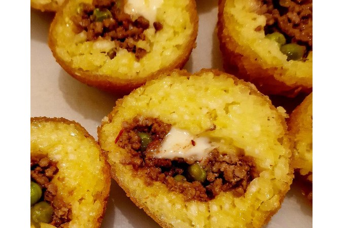 Stuffed rice balls with meat and peas, deep-fried until golden brown, sliced and served on a plate., &copy; Kultweine-Kochwelten-Kunst&uuml;cke - Kochschule Sonja Lenz