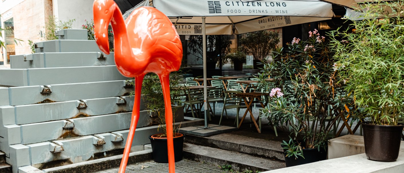 Roter Flamingo vor dem Café Citizen Long mit Sonnenschirmen, Pflanzen und Sitzgelegenheiten im Freien., © SMG Stuttgart Marketing GmbH - Sarah Schmid Roter Flamingo vor dem Café Citizen Long mit Sonnenschirmen, Pflanzen und Sitzgelegenheiten im Freien., © SMG Stuttgart Marketing GmbH - Sarah Schmid