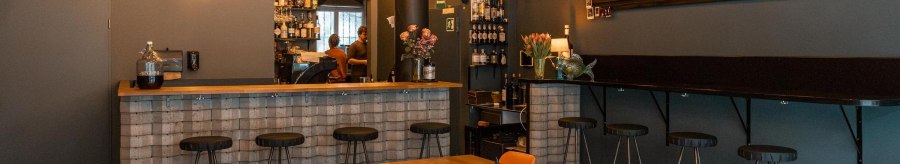 Cozy bar with wooden tables, bar stools and a counter. Fairy lights and a menu board adorn the wall., © SMG, Sarah Schmid
