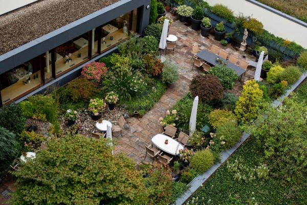 Luftaufnahme eines Gartens mit Terrasse, Tischen, Stühlen und Sonnenschirmen, umgeben von üppiger Vegetation und Pflanzen., © Kronen Hotel GmbH Luftaufnahme eines Gartens mit Terrasse, Tischen, Stühlen und Sonnenschirmen, umgeben von üppiger Vegetation und Pflanzen., © Kronen Hotel GmbH