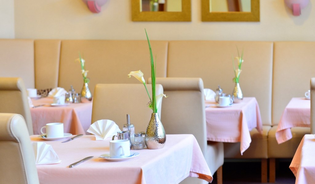 Elegant breakfast room with pink tablecloths, white cups and flower vases. Beige benches and mirror on the wall., © Hotel Fuchsen Elegant breakfast room with pink tablecloths, white cups and flower vases. Beige benches and mirror on the wall., © Hotel Fuchsen