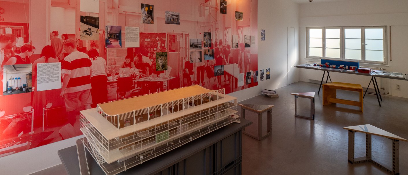 Ausstellung in der Architekturgalerie mit gro&szlig;em Architekturmodell, roten Wandgrafiken, Fotos und Modellen vor einem Fenster., &copy; Thomas F&uuml;tterer