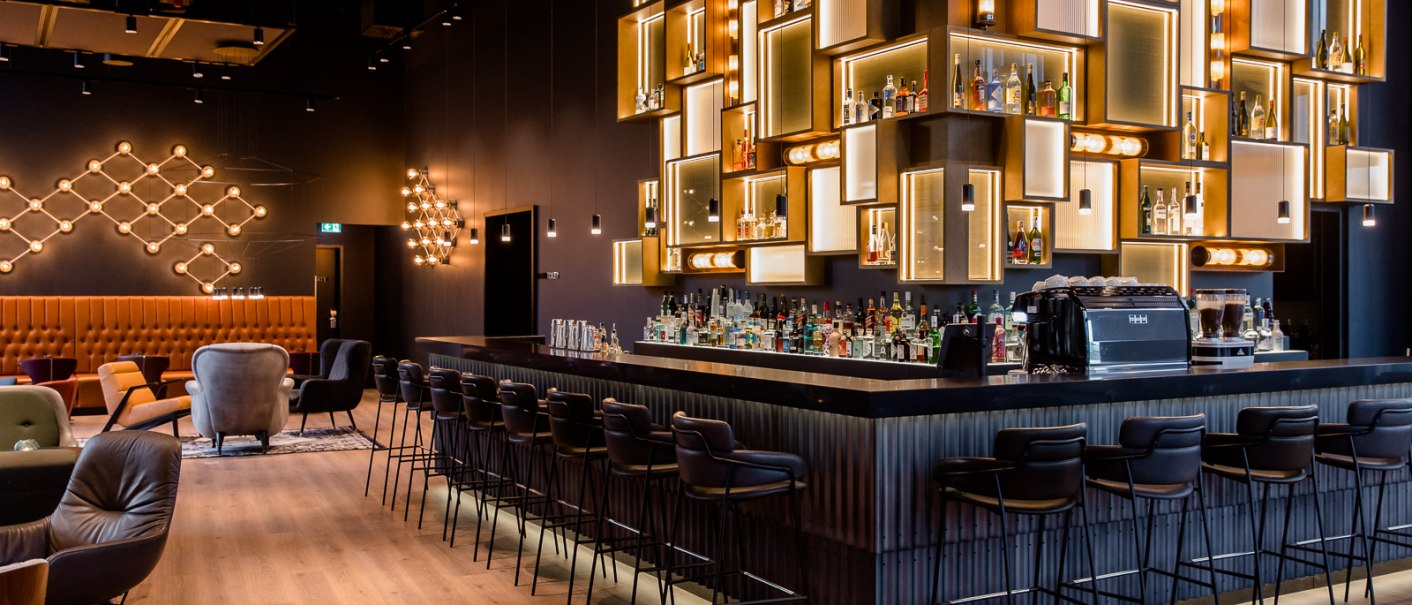 Elegante Bar mit stilvoller Beleuchtung, modernen Sitzgelegenheiten und einer gut bestückten Theke in einem schicken Ambiente., © TOMAS