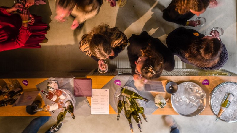 People at a wine tasting, photographed from above. Wine bottles and glasses are on the table. The atmosphere is convivial and relaxed., © club traube People at a wine tasting, photographed from above. Wine bottles and glasses are on the table. The atmosphere is convivial and relaxed., © club traube