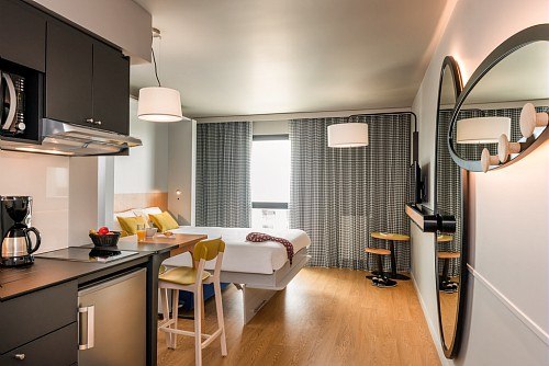 Modern studio with kitchenette, dining table and bed. Large mirrors and windows, bright interior with wooden floor and stylish furniture., &copy; adagio access Stuttgart Airport Messe