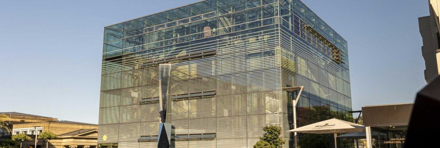 The art museum in Stuttgart with its modern glass façade and a sculpture in front of it, in sunny weather on Kleiner Schlossplatz., © Stuttgart Marketing GmbH, Sarah Schmid