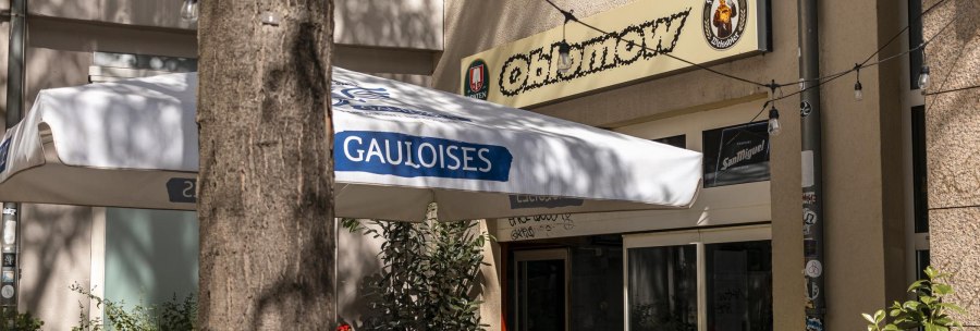 Entrance of a caf&eacute; called Oblamow with Gauloises parasol and plants. Exterior lighting and Franciscan and San Miguel signs visible., &copy; SMG, Sarah Schmid
