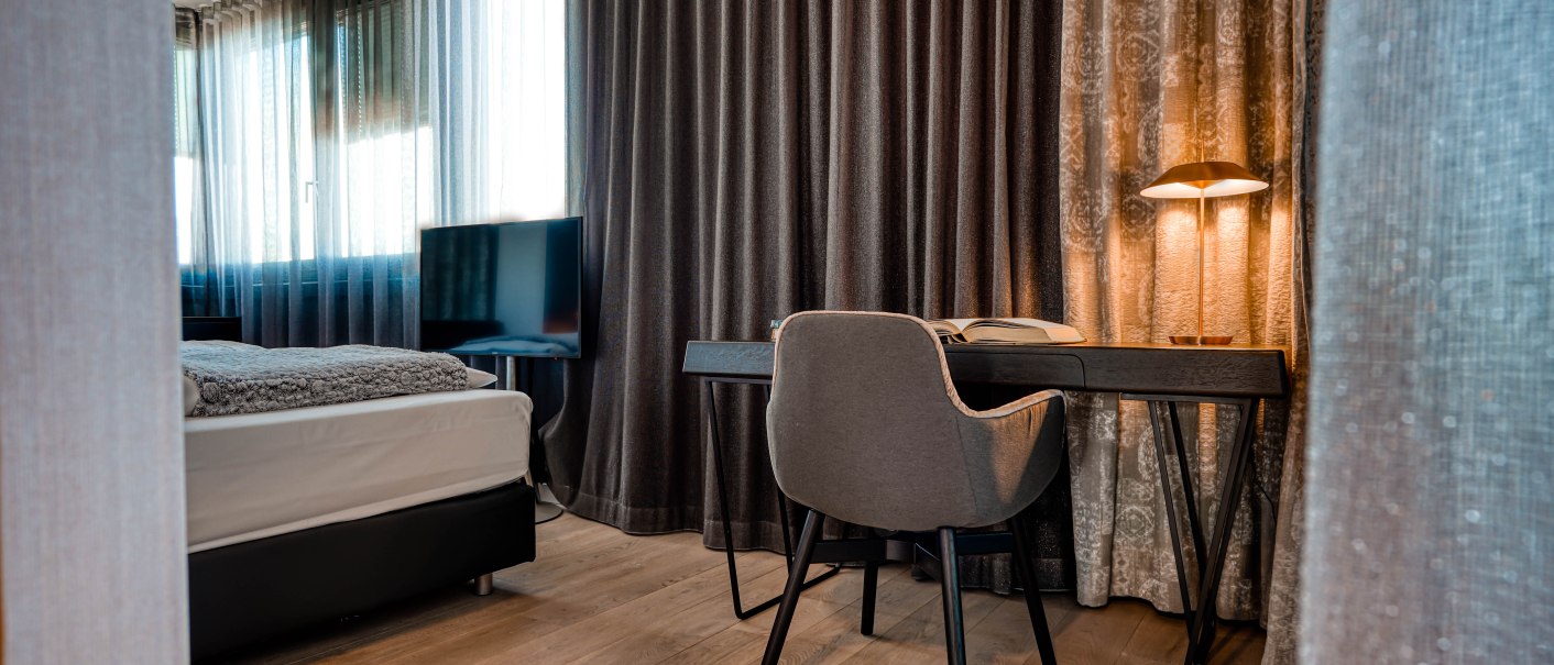 Moderne Penthouse-Suite mit Schreibtisch, Stuhl, Bett und Fernseher. Elegante Vorhänge und warme Beleuchtung schaffen eine gemütliche Atmosphäre., © CLOUD N°7 APARTMENTS GmbH Moderne Penthouse-Suite mit Schreibtisch, Stuhl, Bett und Fernseher. Elegante Vorhänge und warme Beleuchtung schaffen eine gemütliche Atmosphäre., © CLOUD N°7 APARTMENTS GmbH