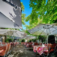 Gartenterrasse mit gedeckten Tischen unter gro&szlig;en Sonnenschirmen, umgeben von &uuml;ppigem Gr&uuml;n und B&auml;umen., &copy; Hotel Gasthof Hasen