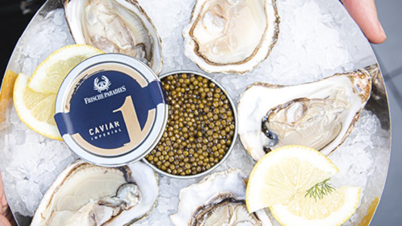 Ein Teller mit frischen Austern und einer Dose Kaviar auf Eis, dekoriert mit Zitronenscheiben. Perfekt f&uuml;r einen luxuri&ouml;sen Genussmoment., &copy; FrischeParadies GmbH & Co. KG