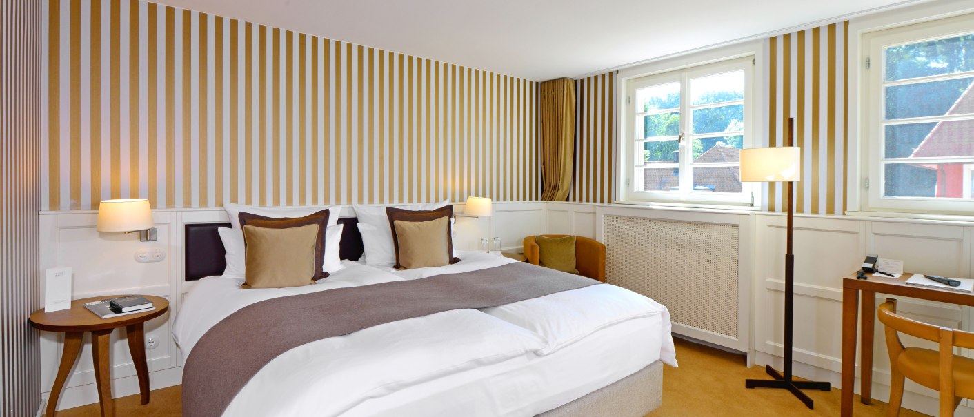 Classic hotel room with striped wallpaper, double bed, desk and floor lamp. Large windows let in plenty of light., © Waldhotel Stuttgart GmbH Classic hotel room with striped wallpaper, double bed, desk and floor lamp. Large windows let in plenty of light., © Waldhotel Stuttgart GmbH
