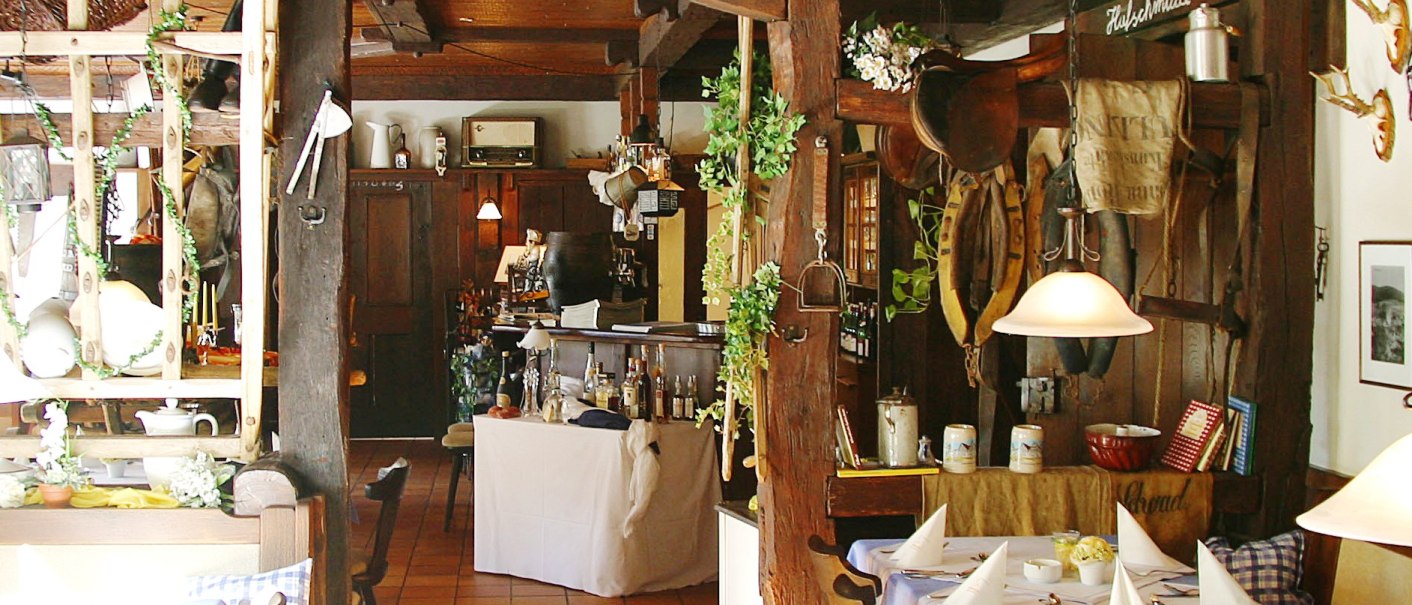 Rustikale Gaststube mit Holzbalken, gedeckten Tischen und gemütlicher Atmosphäre. Dekorationen und Holzmöbel prägen das Ambiente., © R.storr Rustikale Gaststube mit Holzbalken, gedeckten Tischen und gemütlicher Atmosphäre. Dekorationen und Holzmöbel prägen das Ambiente., © R.storr