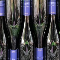 Mehrere Weinflaschen mit blauen Verschl&uuml;ssen stehen dicht nebeneinander. Die Flaschen sind dunkel und reflektieren das Licht., &copy; Weinhof Zai&szlig;