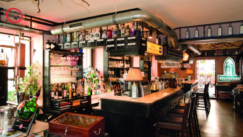 Bar mit Flaschen, Gläsern und Kupferdestille. Klosterfrau-Logo leuchtet im Hintergrund. Gemütliche Atmosphäre mit Holzmöbeln und Lampen., © Buschwerk Mediendesign-Wilhelmer Gastronomie Bar mit Flaschen, Gläsern und Kupferdestille. Klosterfrau-Logo leuchtet im Hintergrund. Gemütliche Atmosphäre mit Holzmöbeln und Lampen., © Buschwerk Mediendesign-Wilhelmer Gastronomie