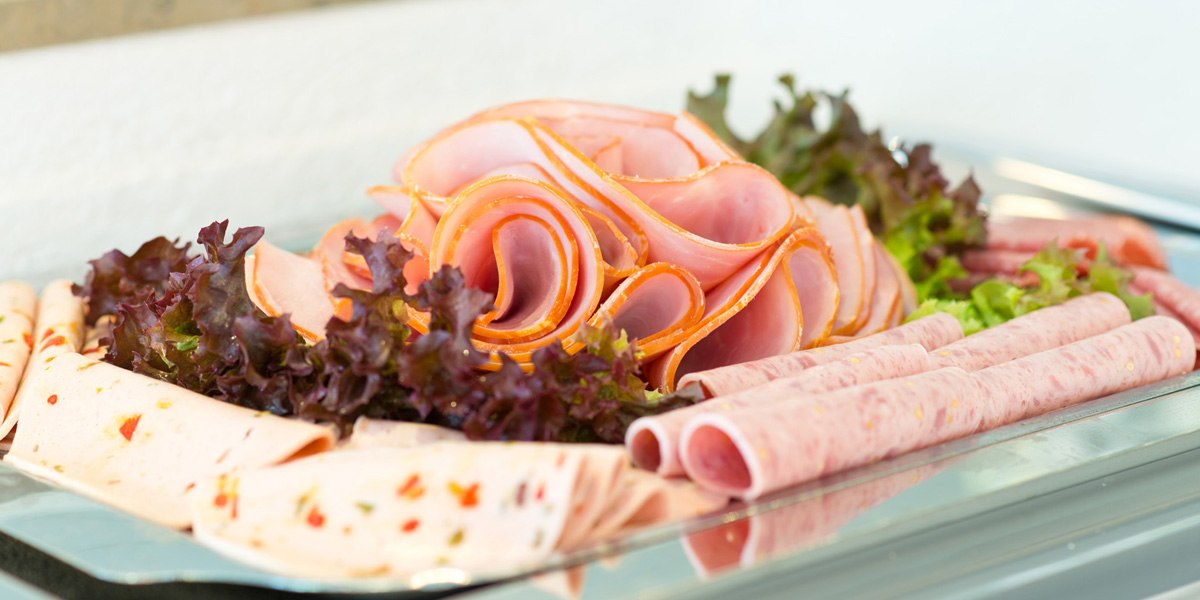 A tray holds various kinds of cold cuts, artfully arranged and garnished with lettuce leaves., &copy; ACHAT Hotels Deutschland