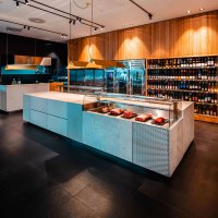 Modernes Fleischgeschäft mit eleganter Theke, Fleischpräsentation und großem Weinregal an der Wand. Stilvolle Beleuchtung und Holzverkleidung., © The Meat Club, Stuttgart Modernes Fleischgeschäft mit eleganter Theke, Fleischpräsentation und großem Weinregal an der Wand. Stilvolle Beleuchtung und Holzverkleidung., © The Meat Club, Stuttgart