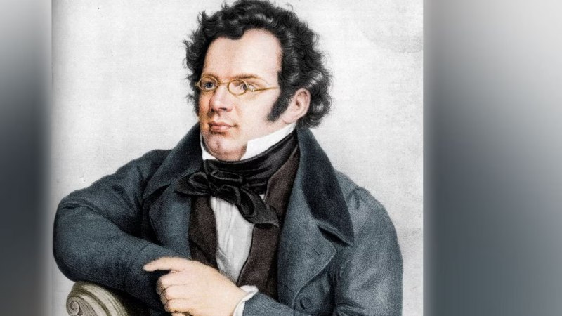 Ein Mann mit Brille und lockigem Haar in einem eleganten Anzug sitzt mit verschränkten Armen., © Heritage Images Ein Mann mit Brille und lockigem Haar in einem eleganten Anzug sitzt mit verschränkten Armen., © Heritage Images